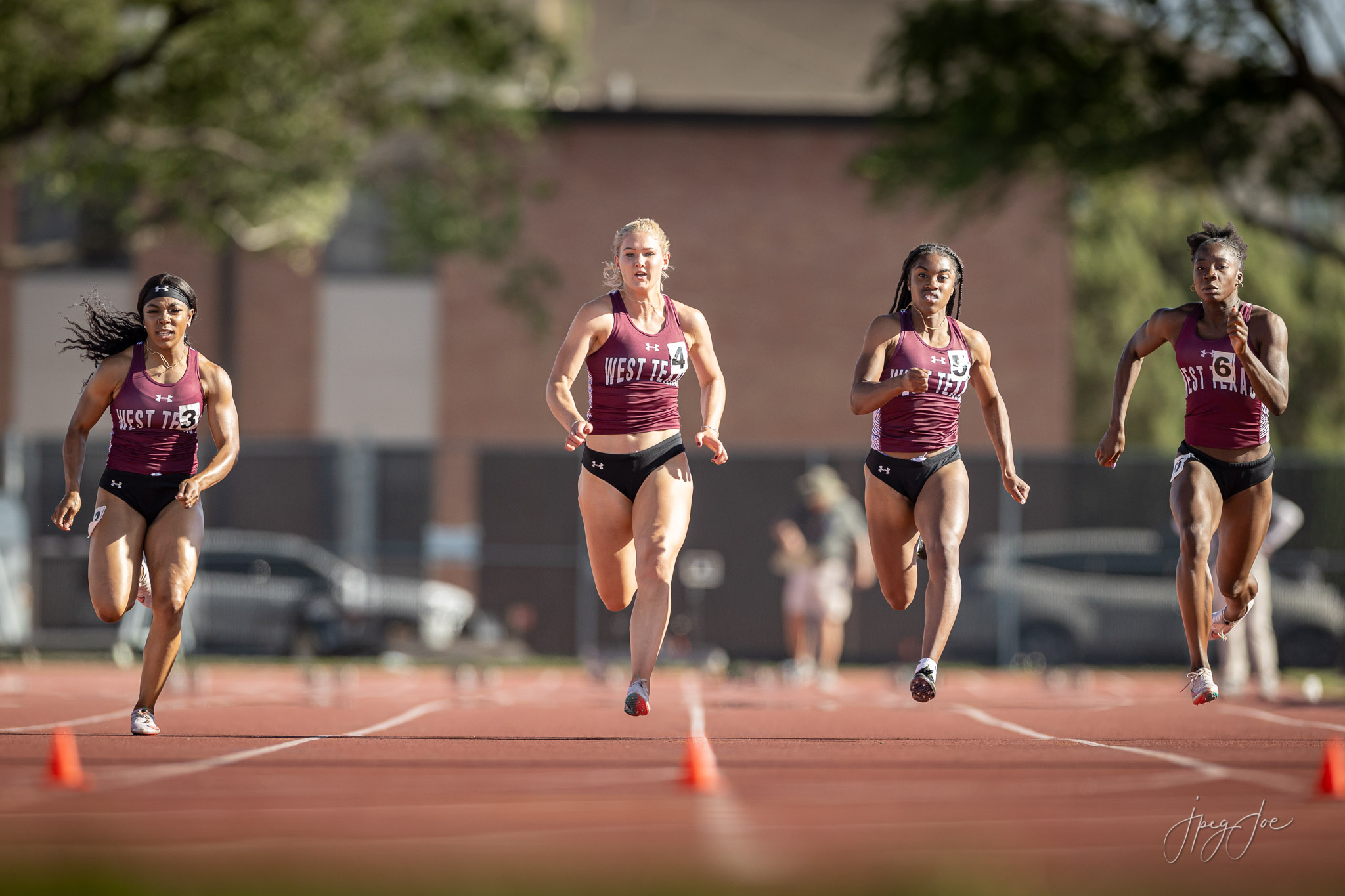 A group of WTAMU female athletes run down the track at the 2021 Lone Star Conference Track meet.